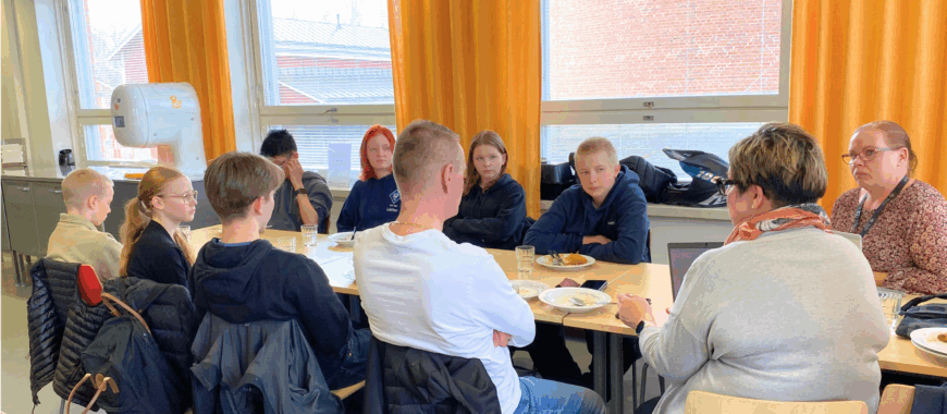 aikuiset ja nuoret keskustelevat yhteisen pöydän ääressä