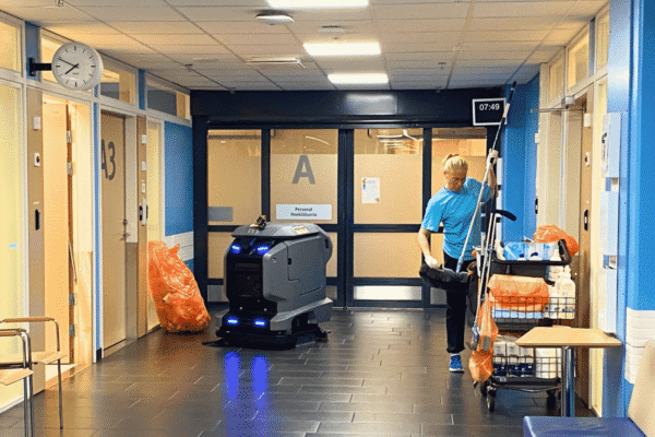 Städare tar fram en ny moppduk, roboten kör i bakgrunden
